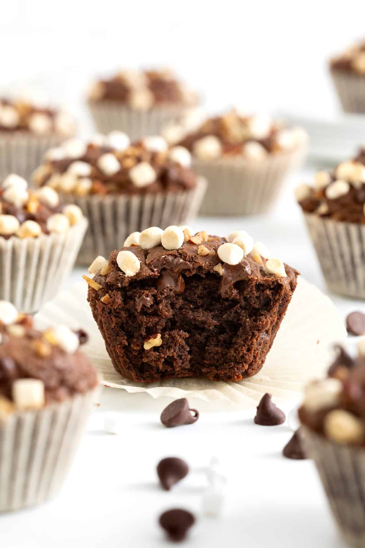 A rocky road brownie cupcake with a bite taken out of it.