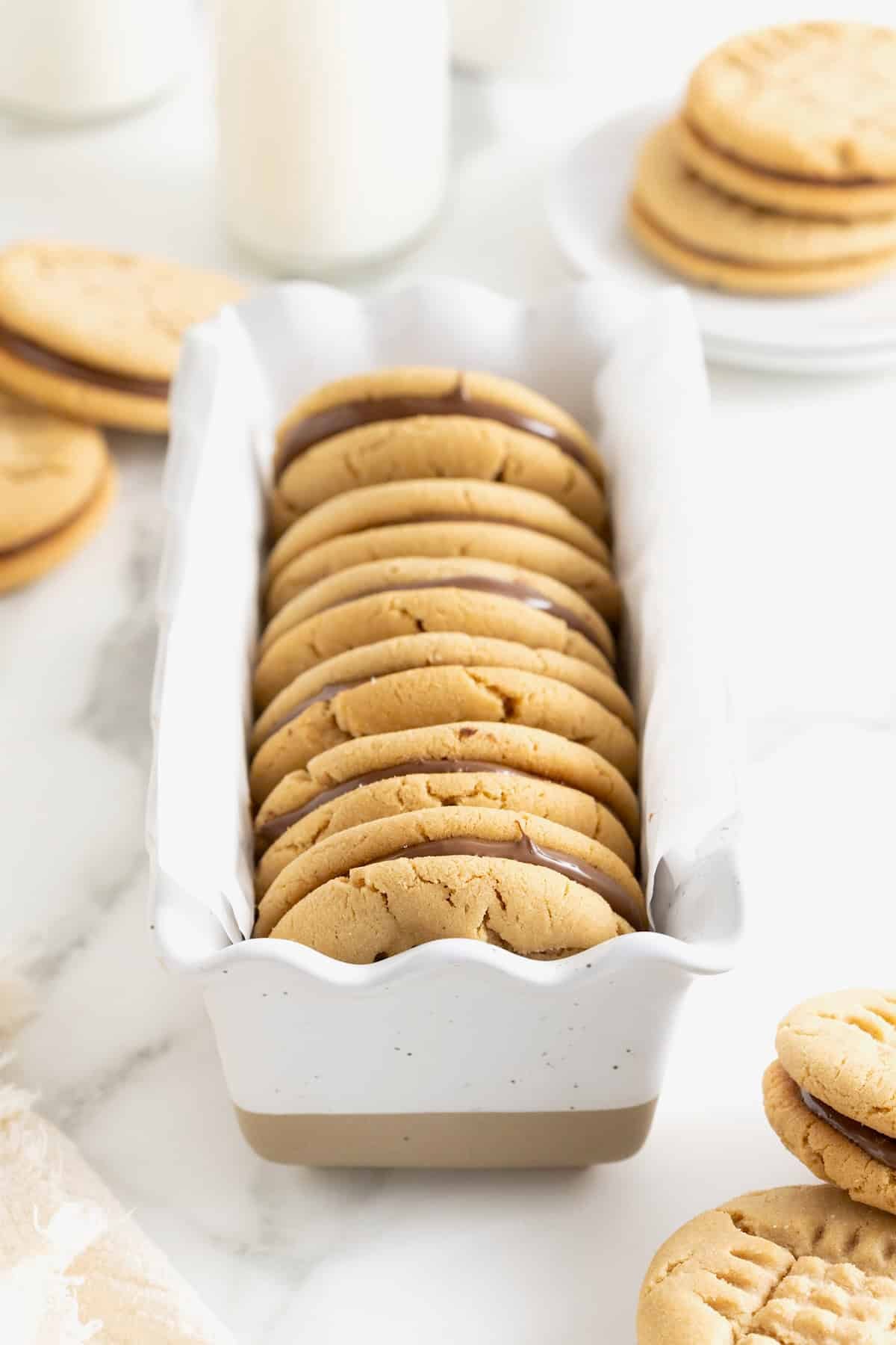 Six peanut butter cookie sandwiches in a white dish.