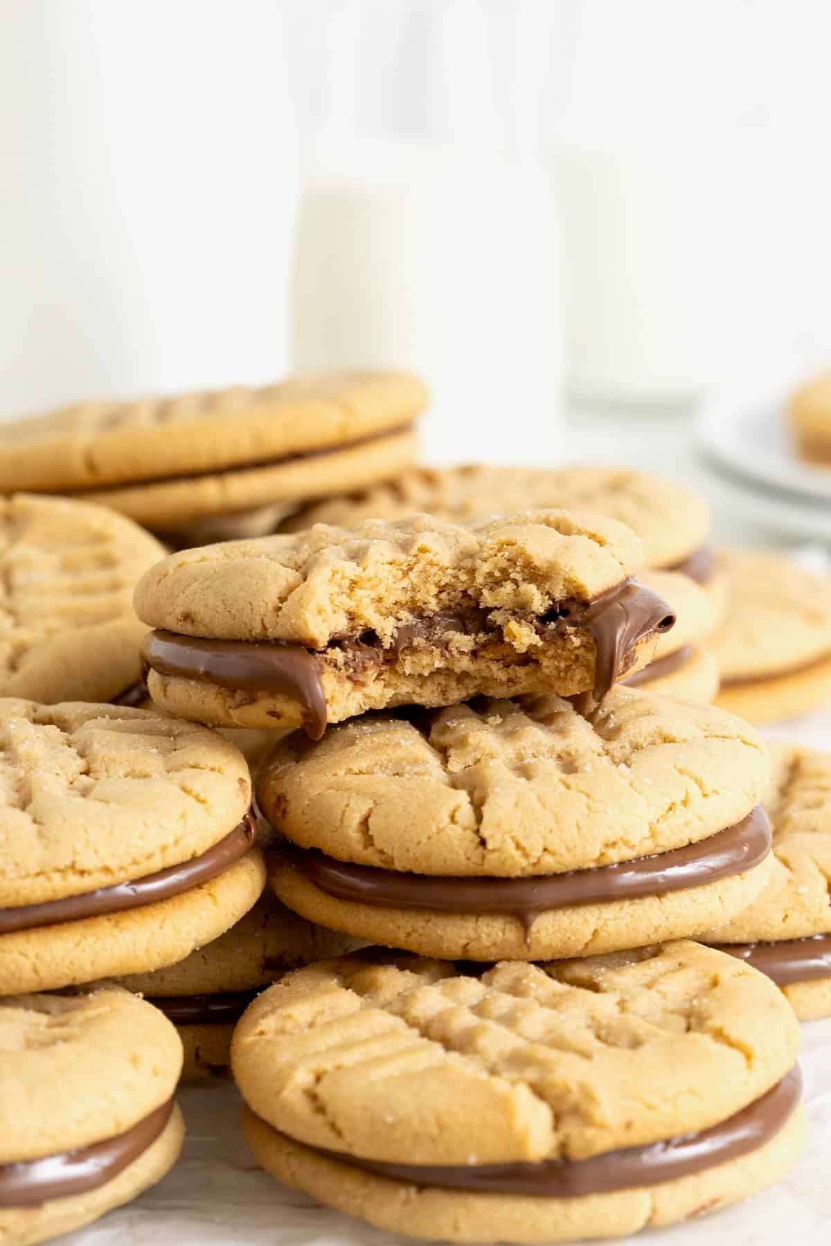 A pile of peanut butter sandwich cookies. The top cookie has a bite out of it.
