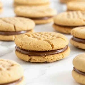 10 peanut butter cookie sandwiches with a chocolate hazelnut filling on a white marble surface.
