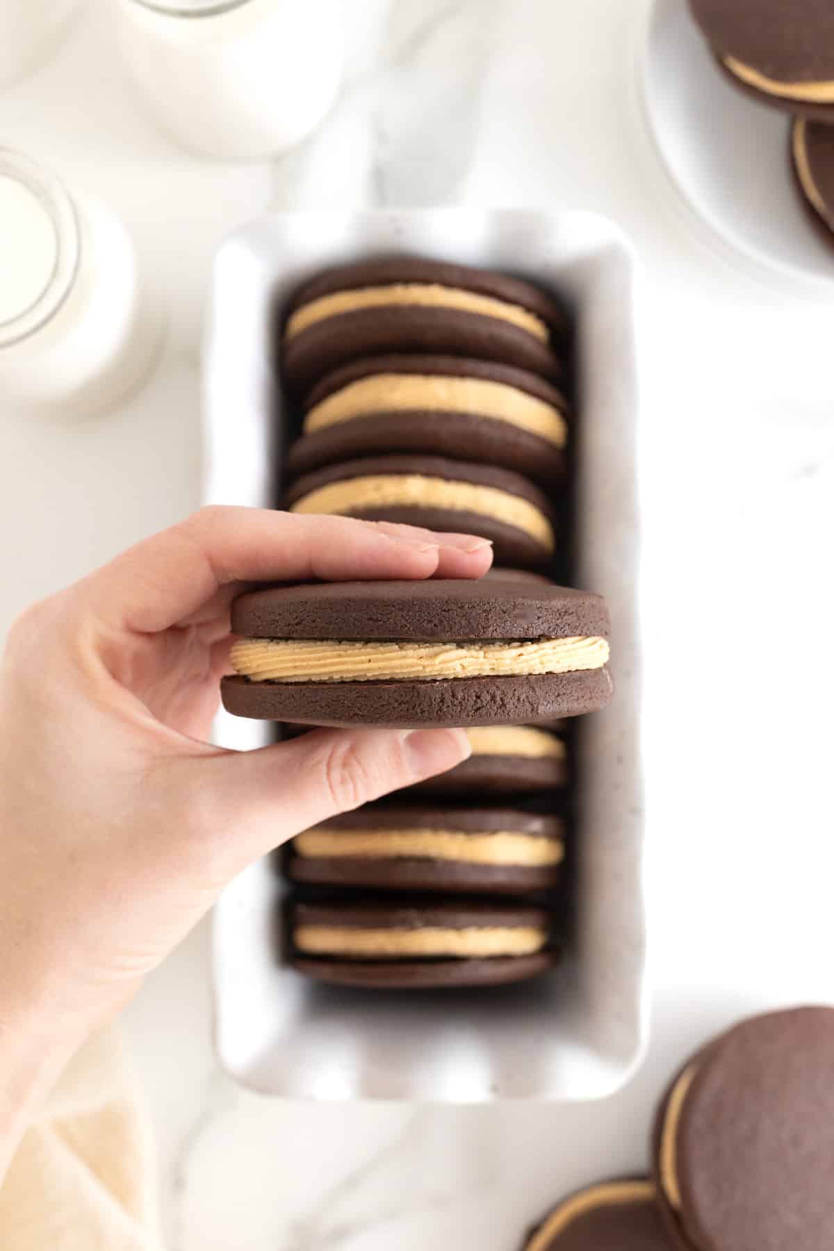 A hand holding a peanut butter cream filed chocolate sandwich cookie.