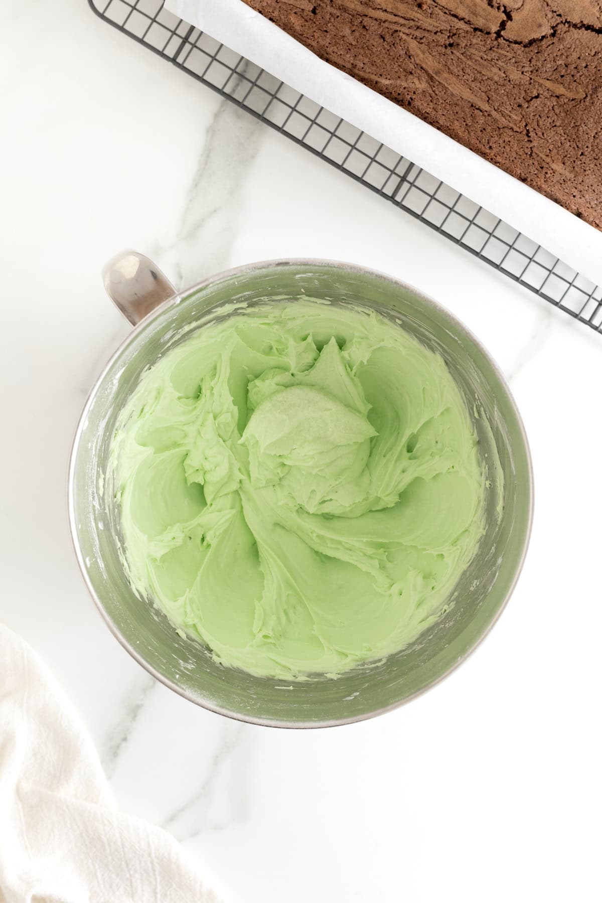 Green frosting in the bowl of an electric mixer.