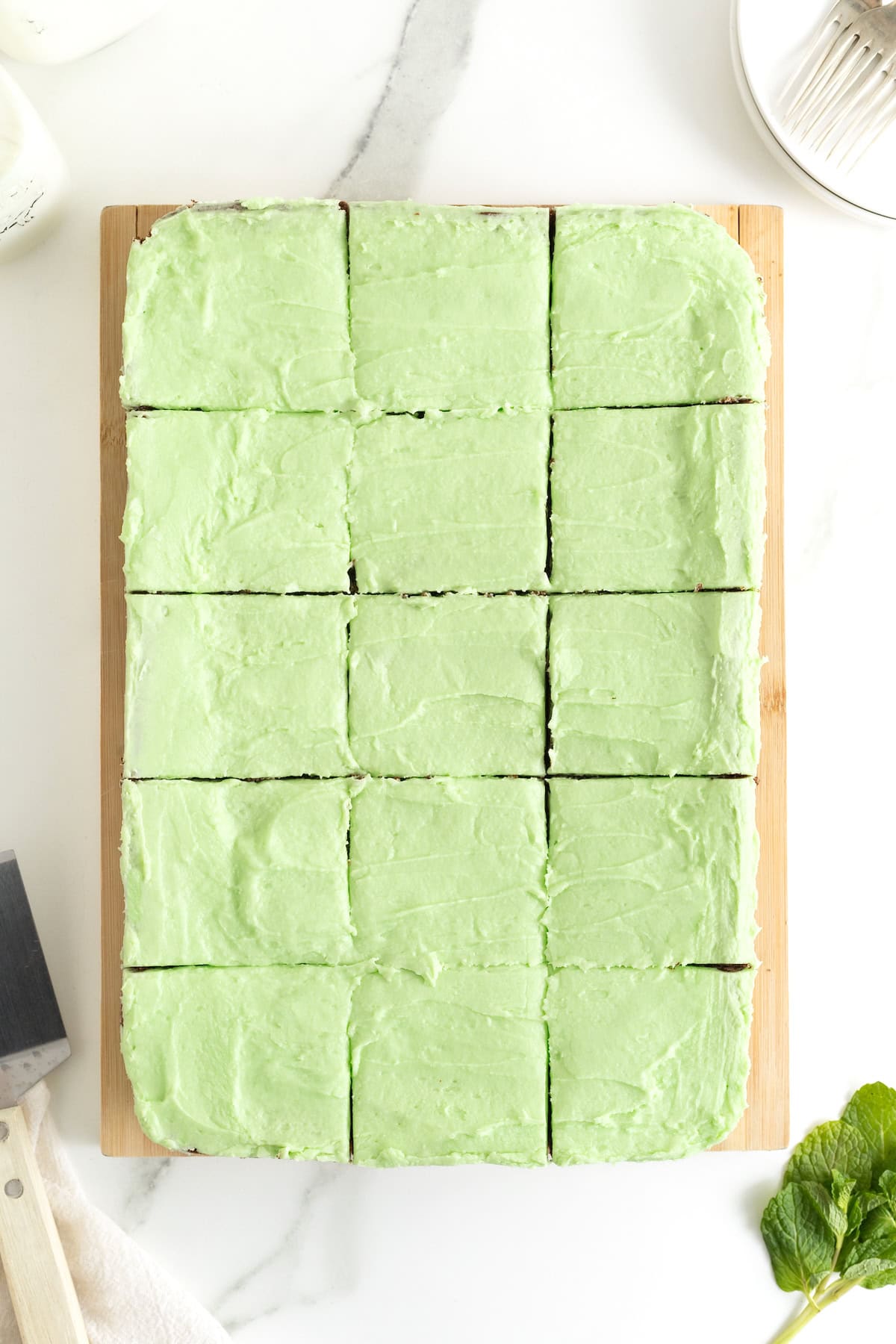 12 mint julep brownies on a parchment lined wooden cutting board.