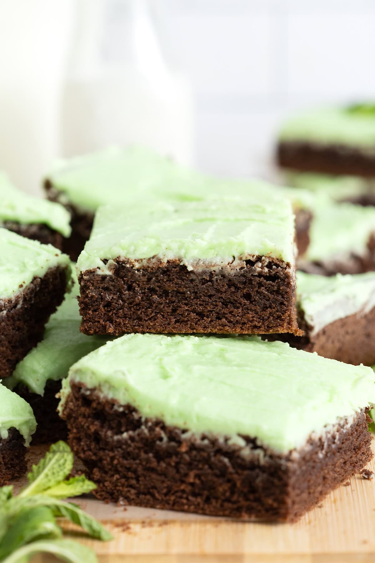 A pile of mint julep brownies on a wood cutting board.