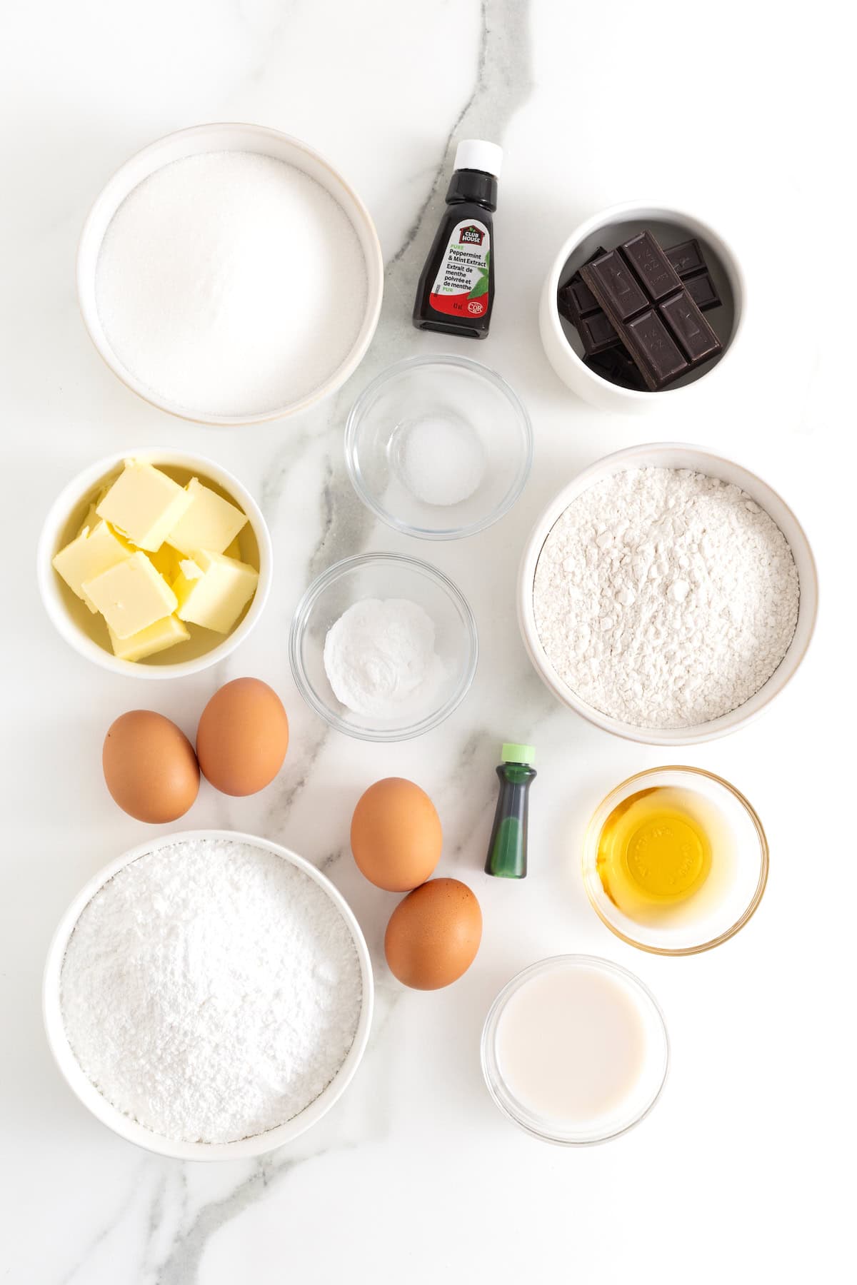 Ingredients to make mint julep brownies in small white dishes on a white marble counter.