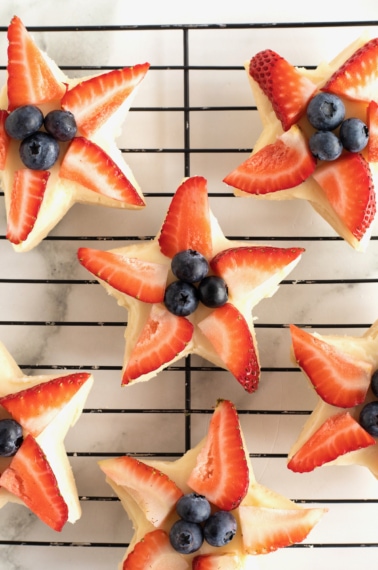 Star shaped shortbread cookies with strawberry slices and blueberries in the center.
