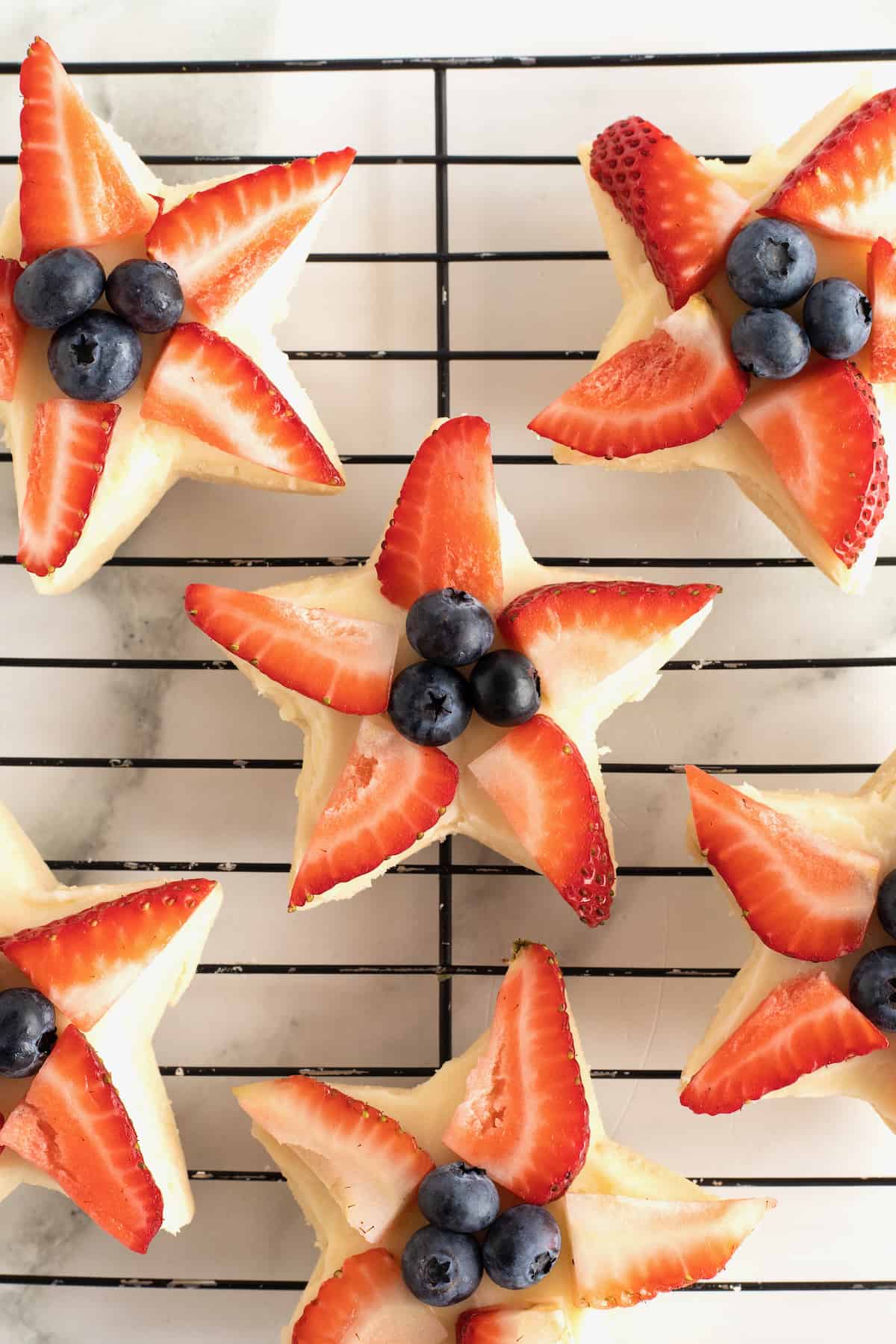 Star shaped shortbread cookies with strawberry slices and blueberries in the center.