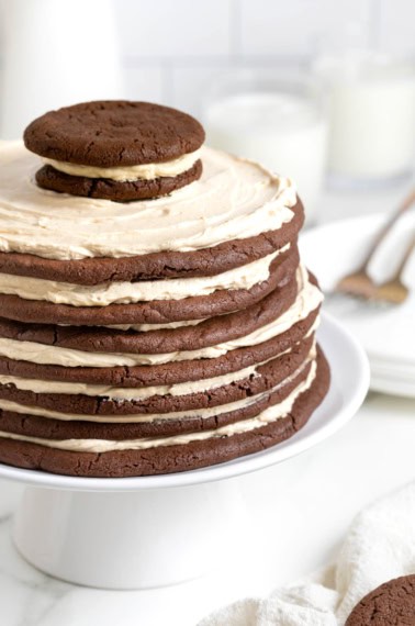 A chocolate peanut butter layered cookie cake on a white cake stand.