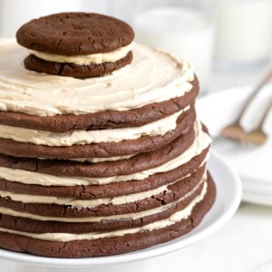 A chocolate peanut butter layered cookie cake on a white cake stand.