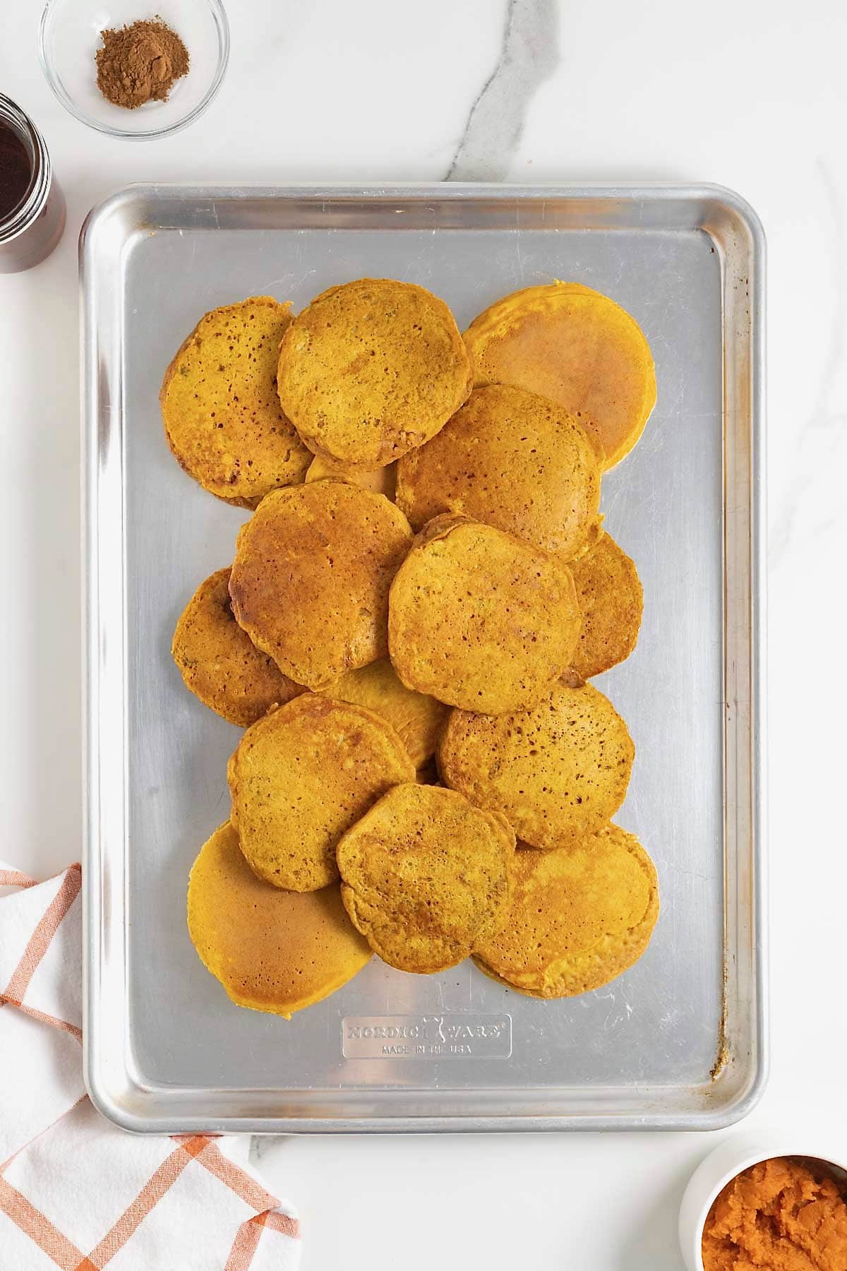 Pumpkin banana pancakes on an aluminum baking sheet.