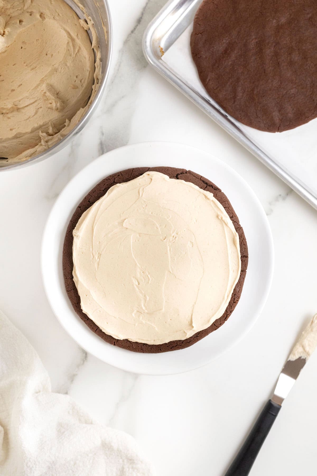 A layer of peanut butter filling on a large chocolate cookie layer.