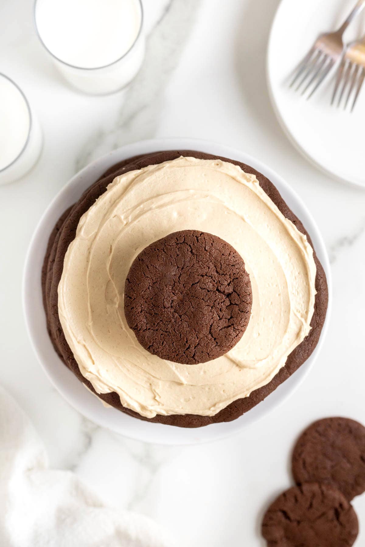 Top view of a chocolate peanut butter layered cookie cake on a white cake stand on a white marble counter.