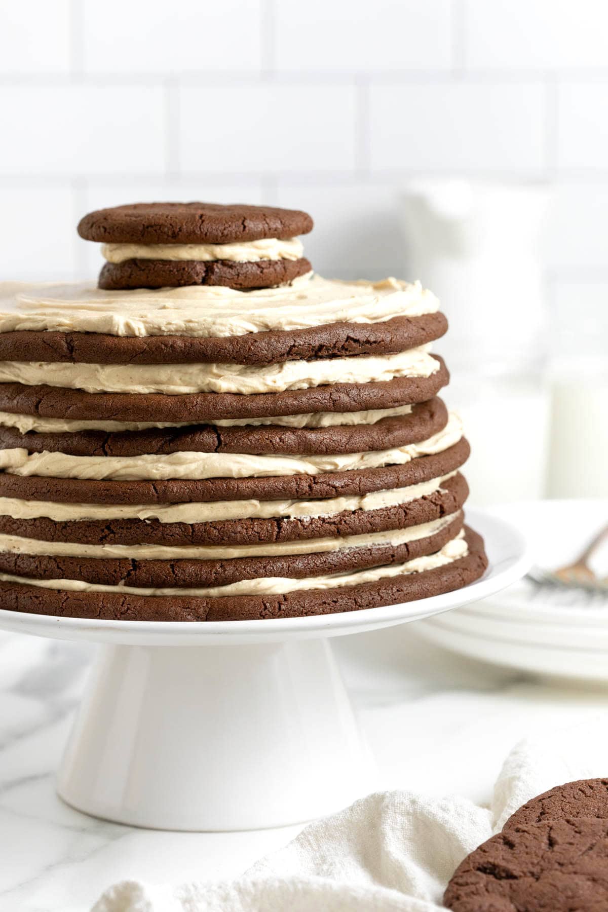 A chocolate peanut butter layered cookie cake on a white cake stand.