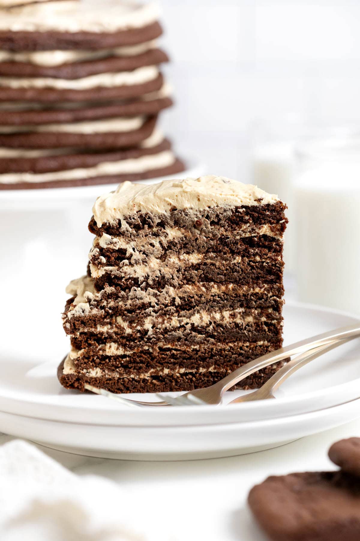 A slice of chocolate peanut butter cookie layer cake on a white plate next to a fork.