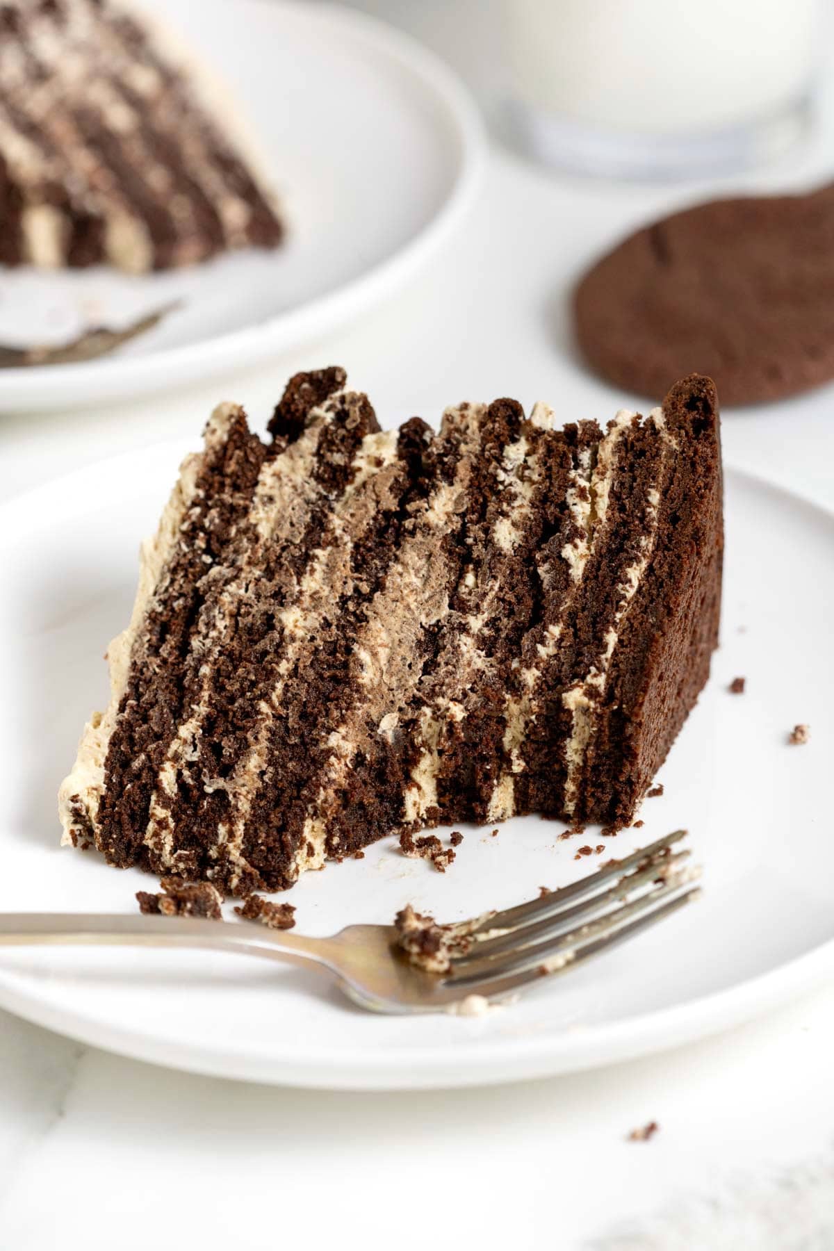 A slice of chocolate peanut butter layered cookie cake on a white plate with a metal fork.