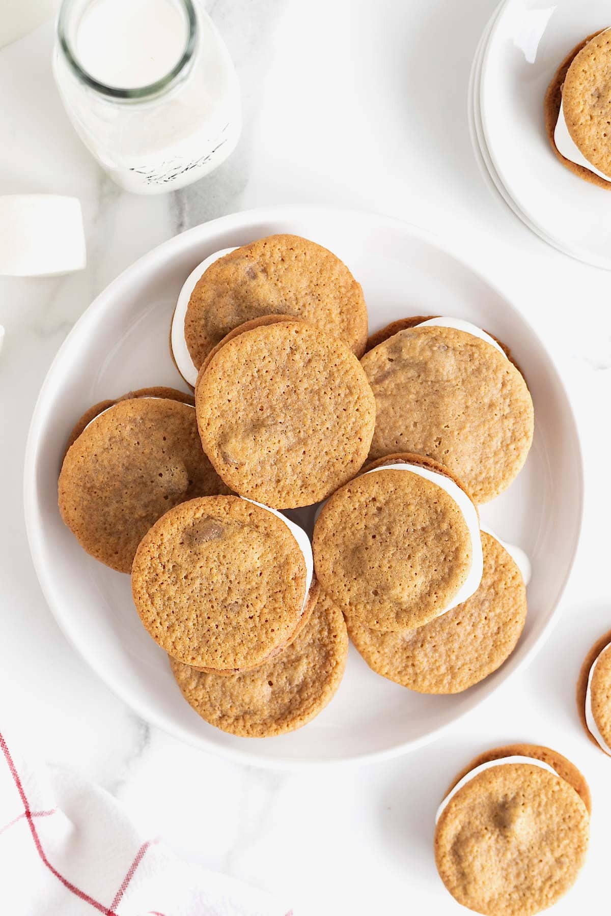 A white rimmed serving platter piled with s'mores ice cream sandwiches.