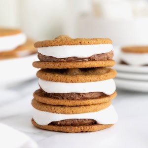 A stack of three s'mores ice cream sandwiches on a white marble surface.