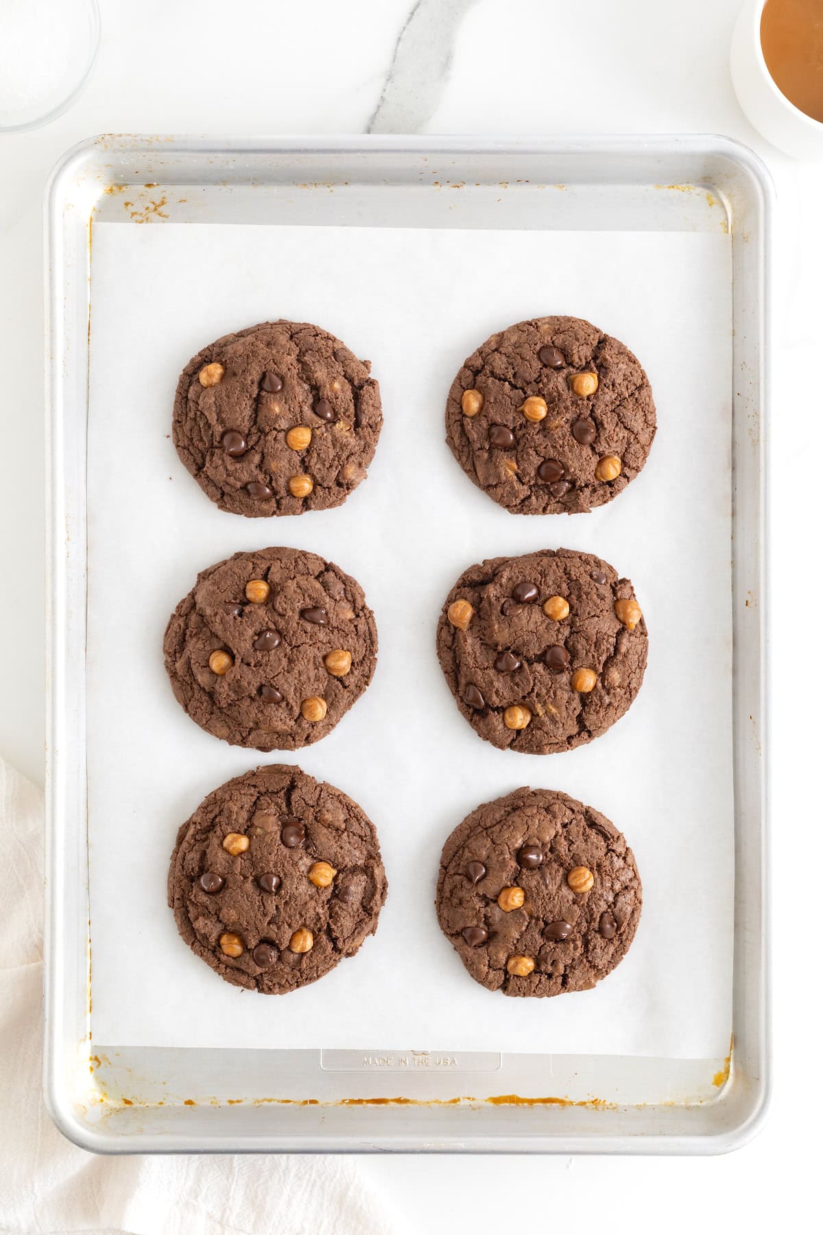 Six dark chocolate cookies on a parchment lined cookie sheet.