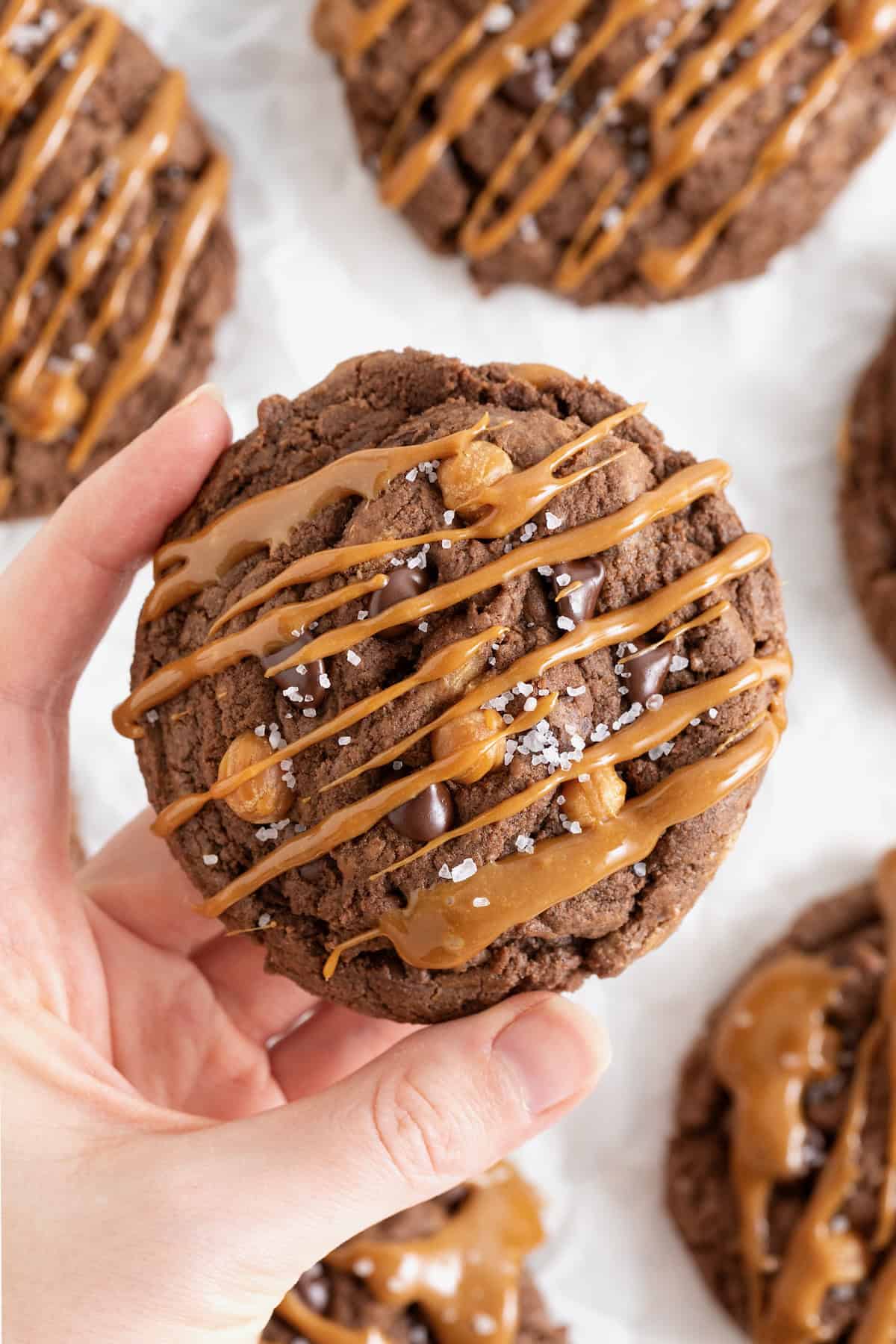 A large chocolate cookie with chocolate chips and caramel bits drizzled in caramel sauce.