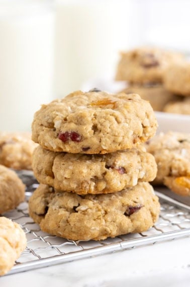 Three coconut oatmeal cookies stacked on a wire cooling rack.