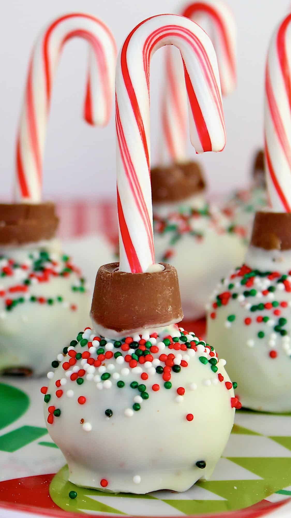 Christmas treats that look like ornaments, with a mini candy cane on top.