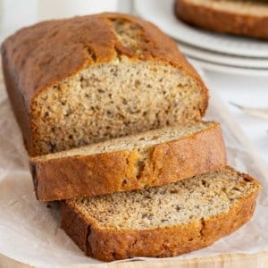 A loaf brown butter banana bread loaf on a parchment covered wooden cutting board.