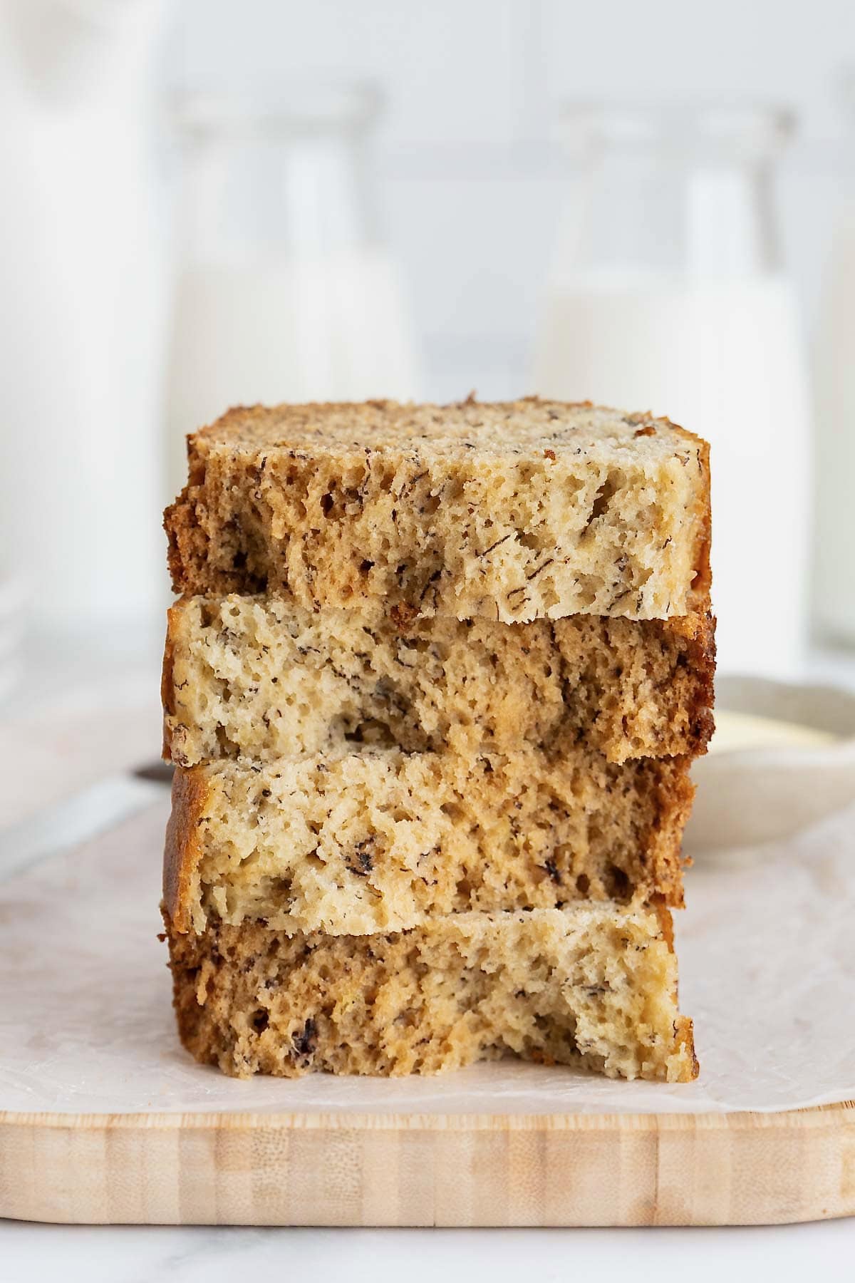 A stack of four pieces of brown butter banana bread on a white surface.