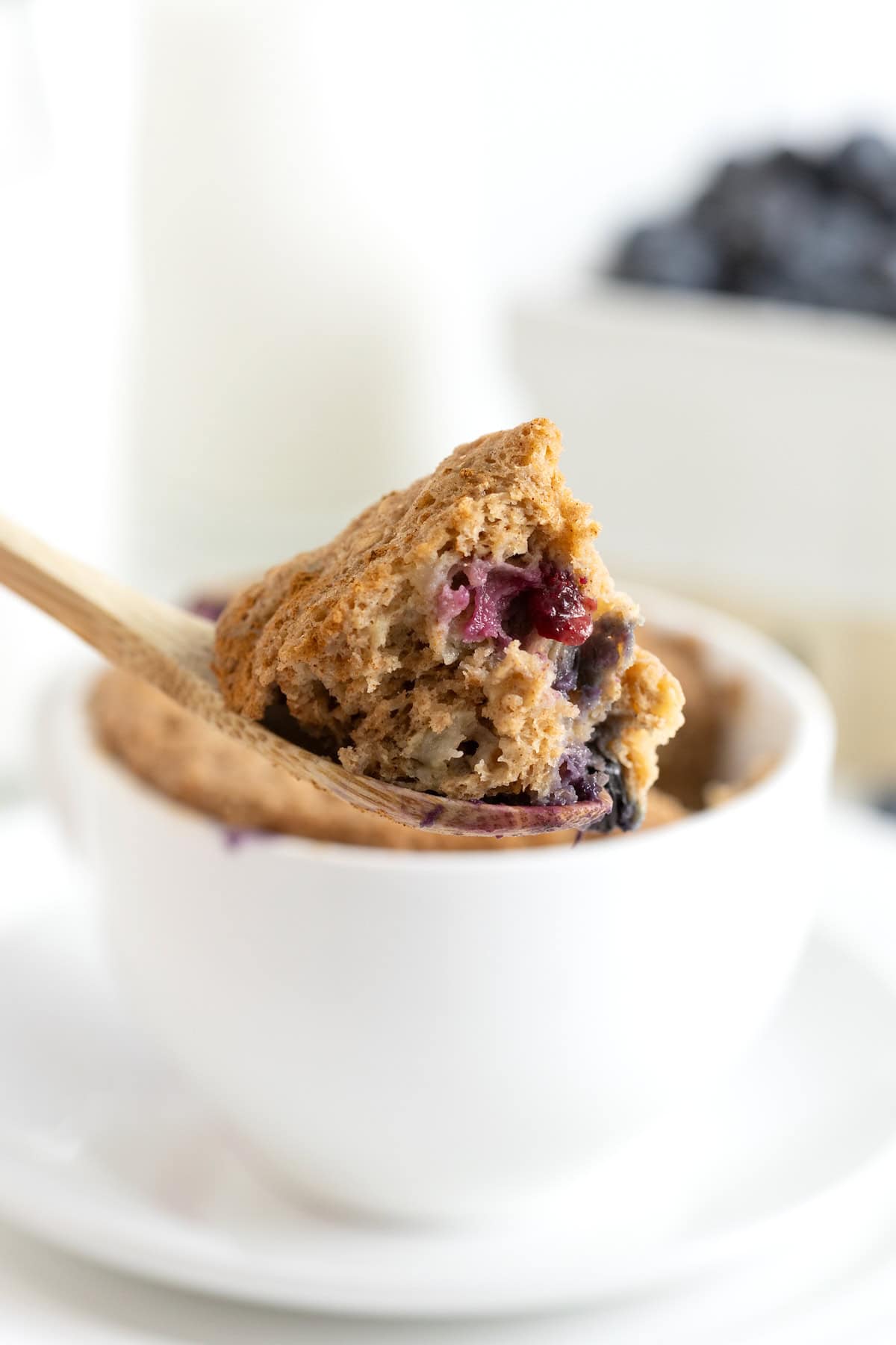 A bite of banana blueberry muffin on a wooden spoon.