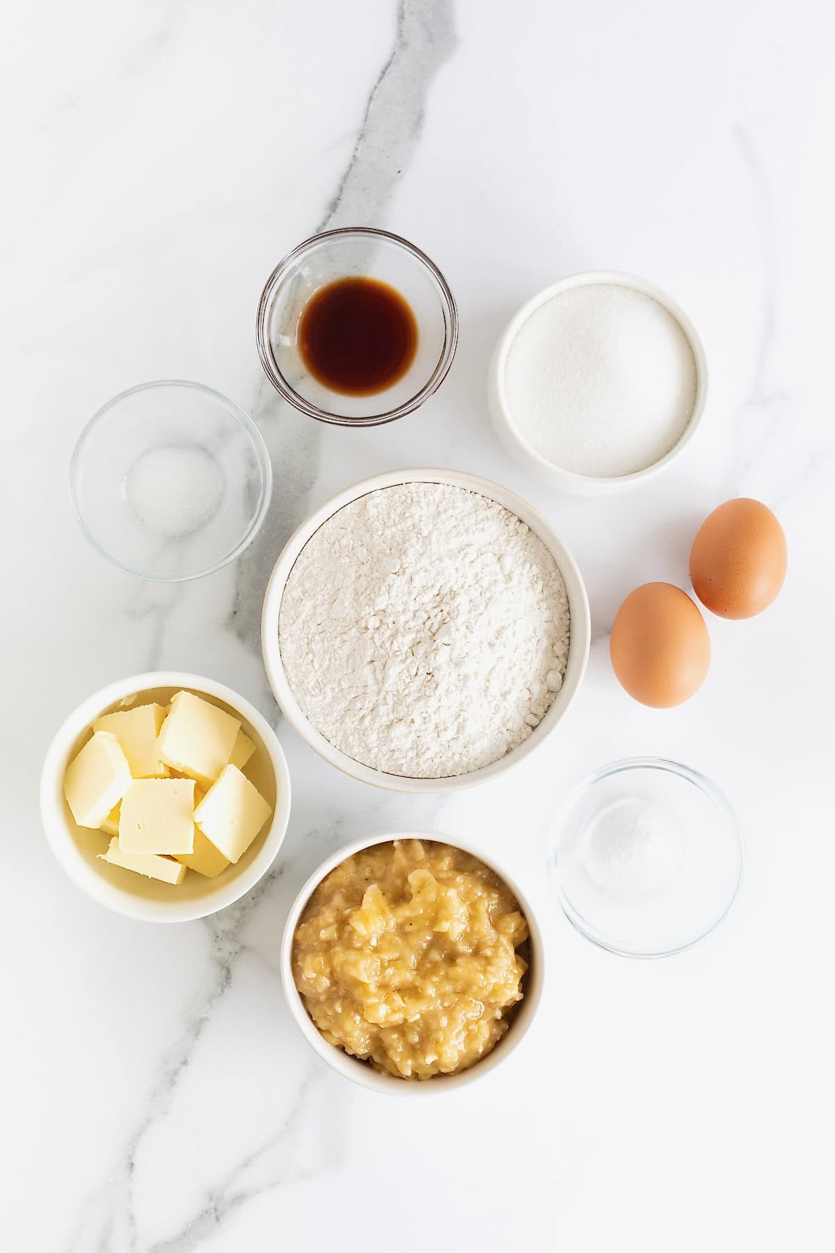Ingredients to make brown butter banana bread in small dishes on a white marble counter.