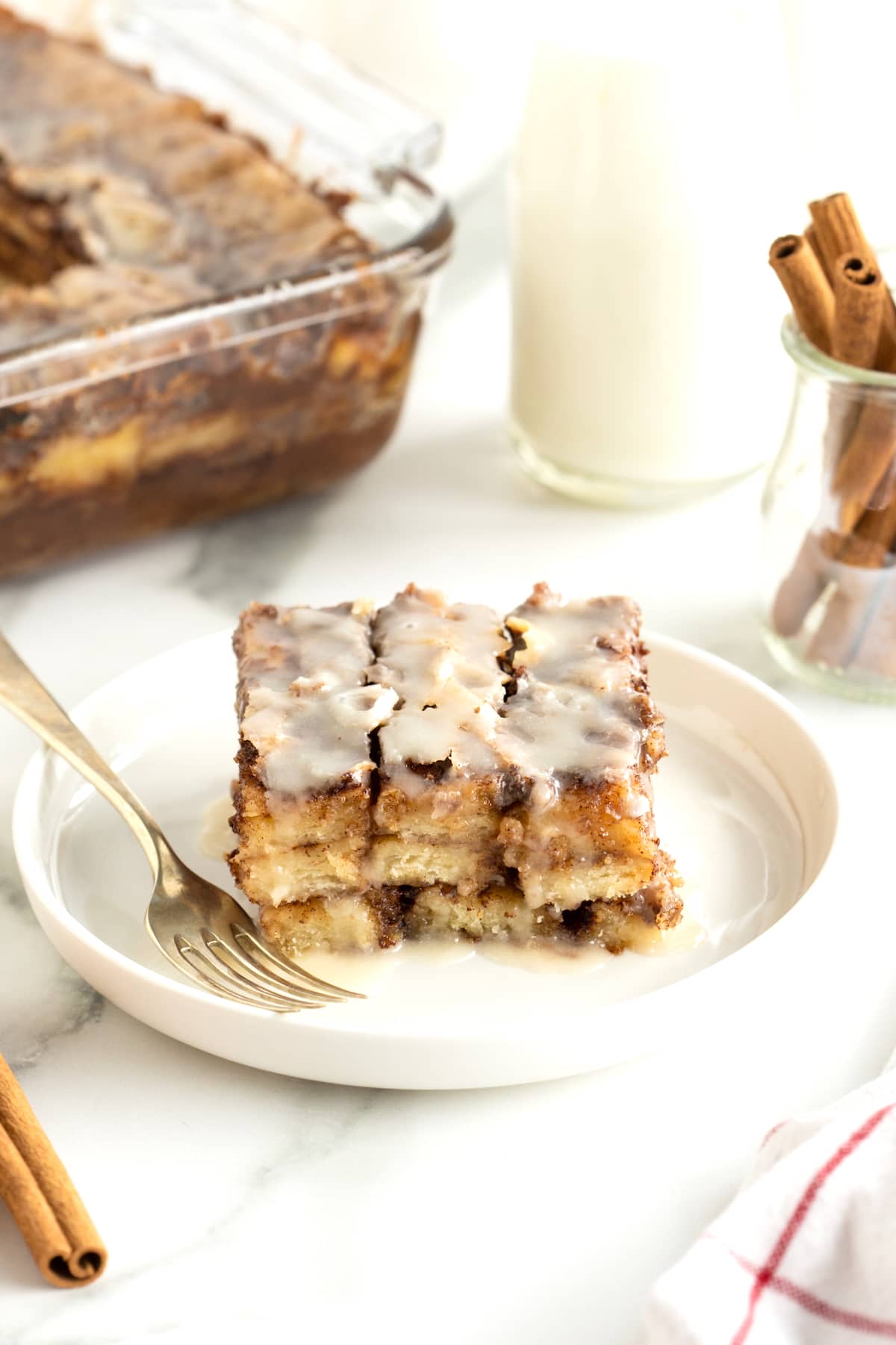 A piece of cinnamon roll lasagna on a white plate with a fork.