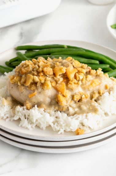 A white dinner plate with a serving of creamy chicken bake on top of a bed of rice.
