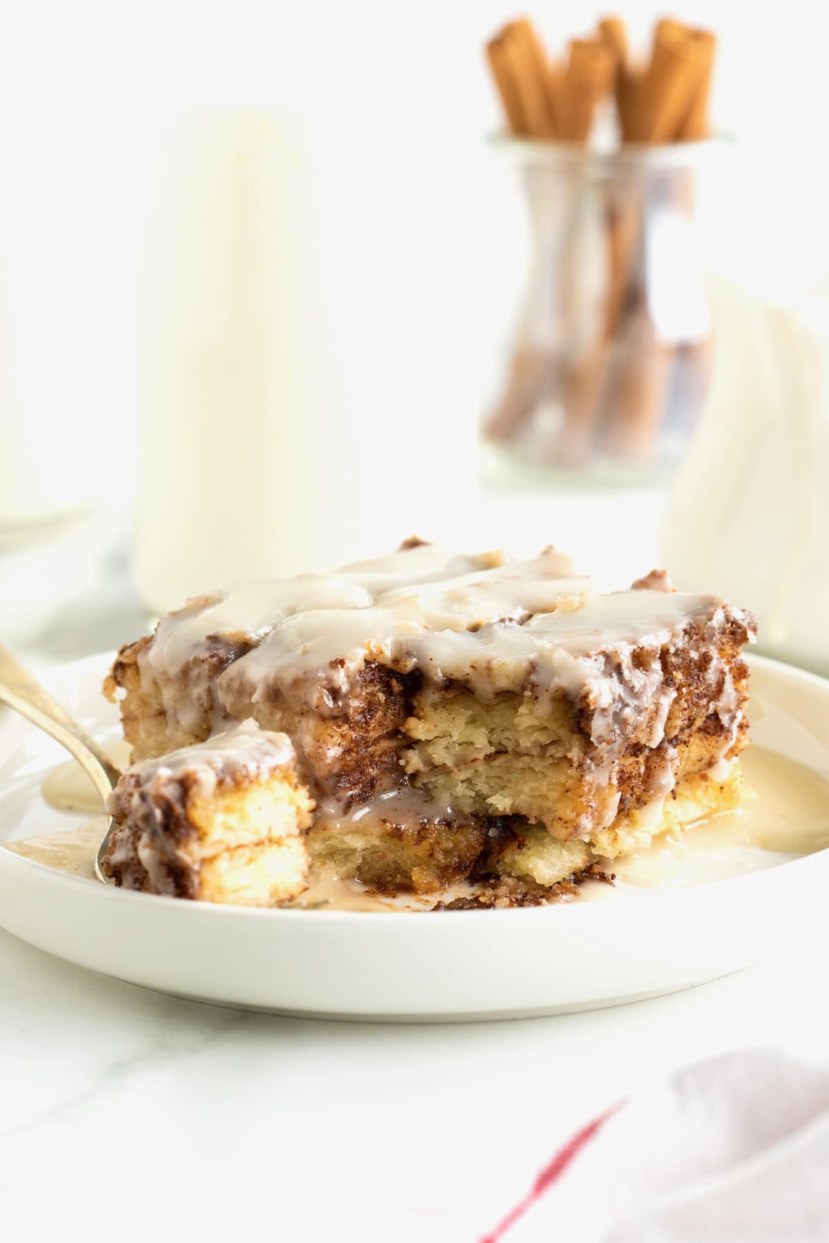 A piece of cinnamon roll lasagna on a white plate with a fork.