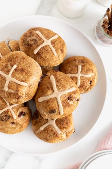 A white platter piled with cranberry hot cross buns.
