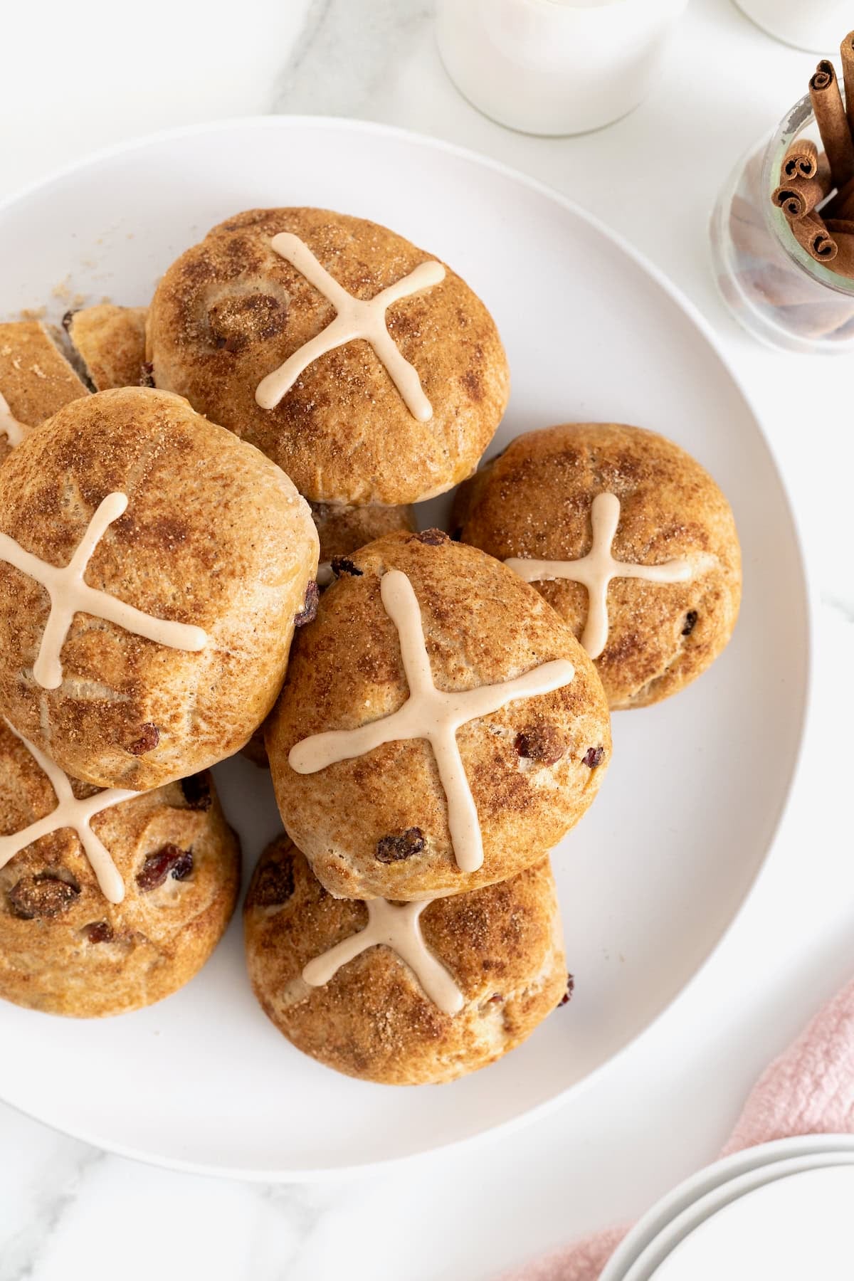 A white platter piled with cranberry hot cross buns.