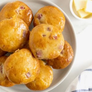 A white platter of honey glazed ham and cheddar muffins.