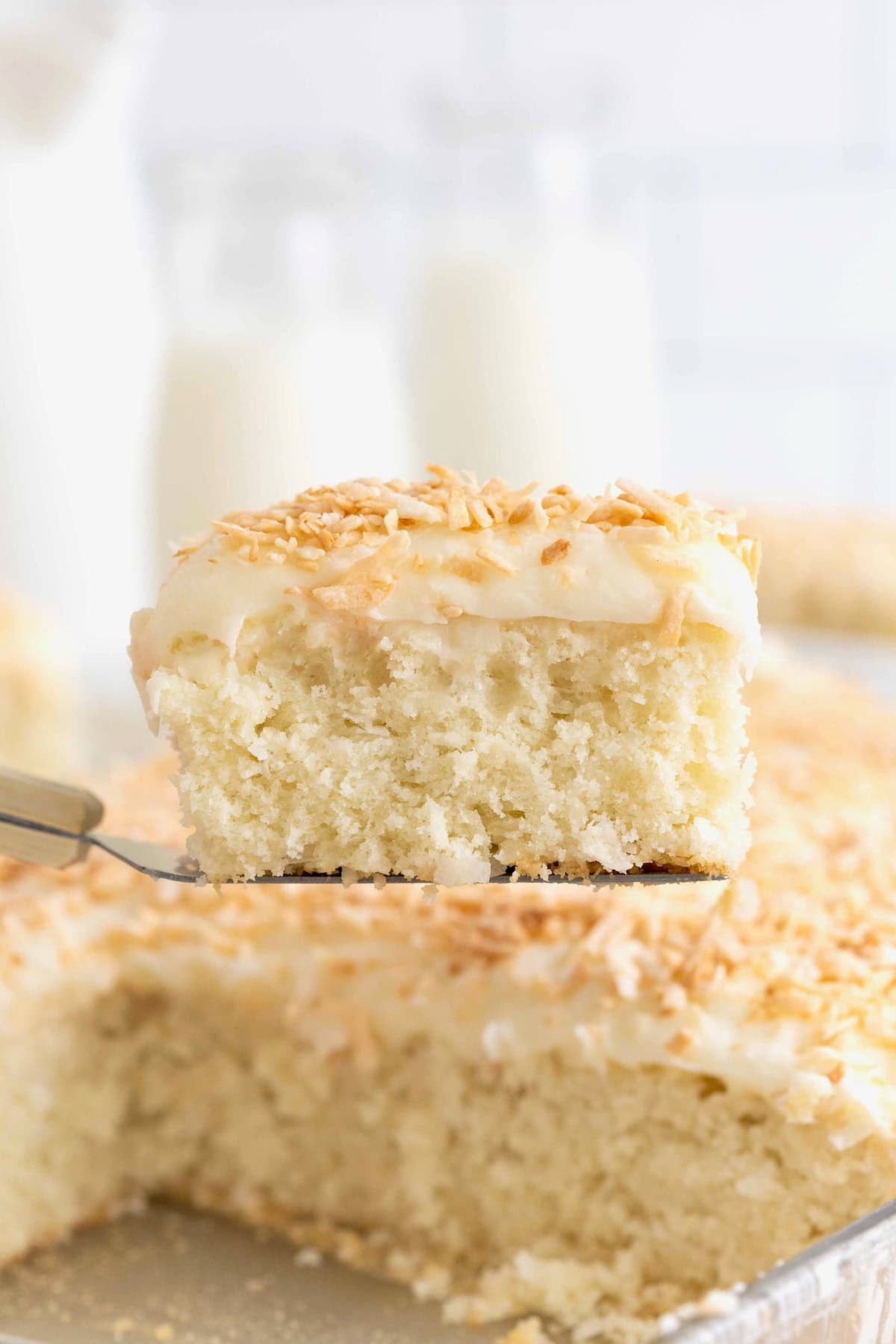 A slice of coconut cream sheet cake on a spatula.