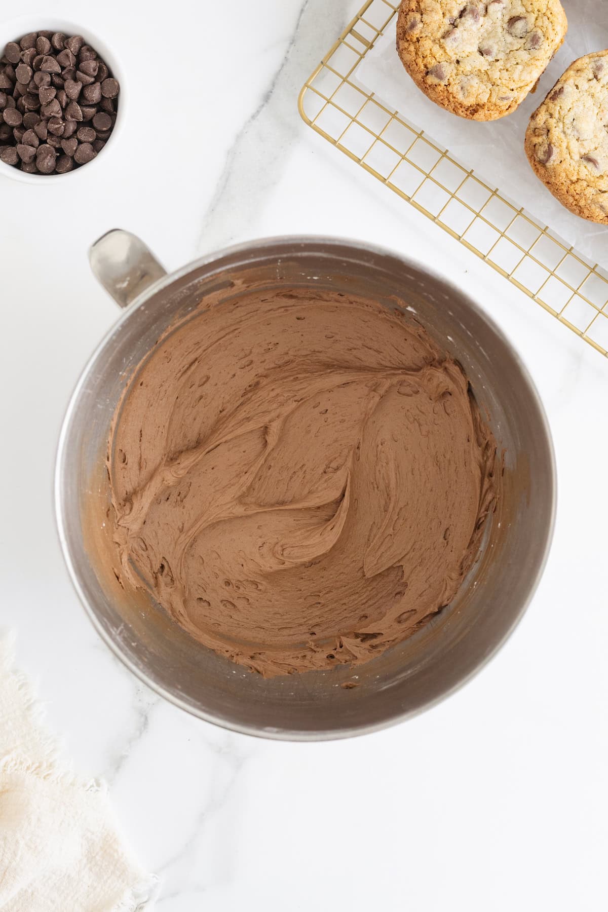 A stainless steel mixing bowl of chocolate frosting.