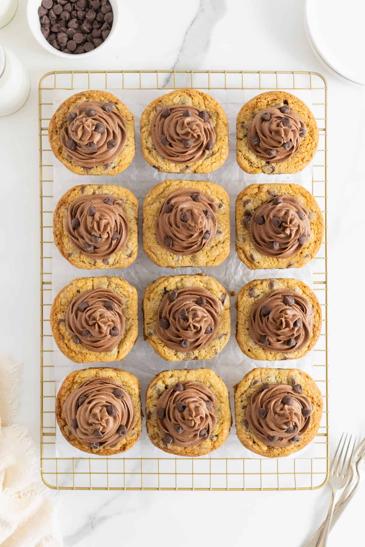Twelve cookie cup cupcakes frosted with chocolate frosting and garnished with chocolate chips.
