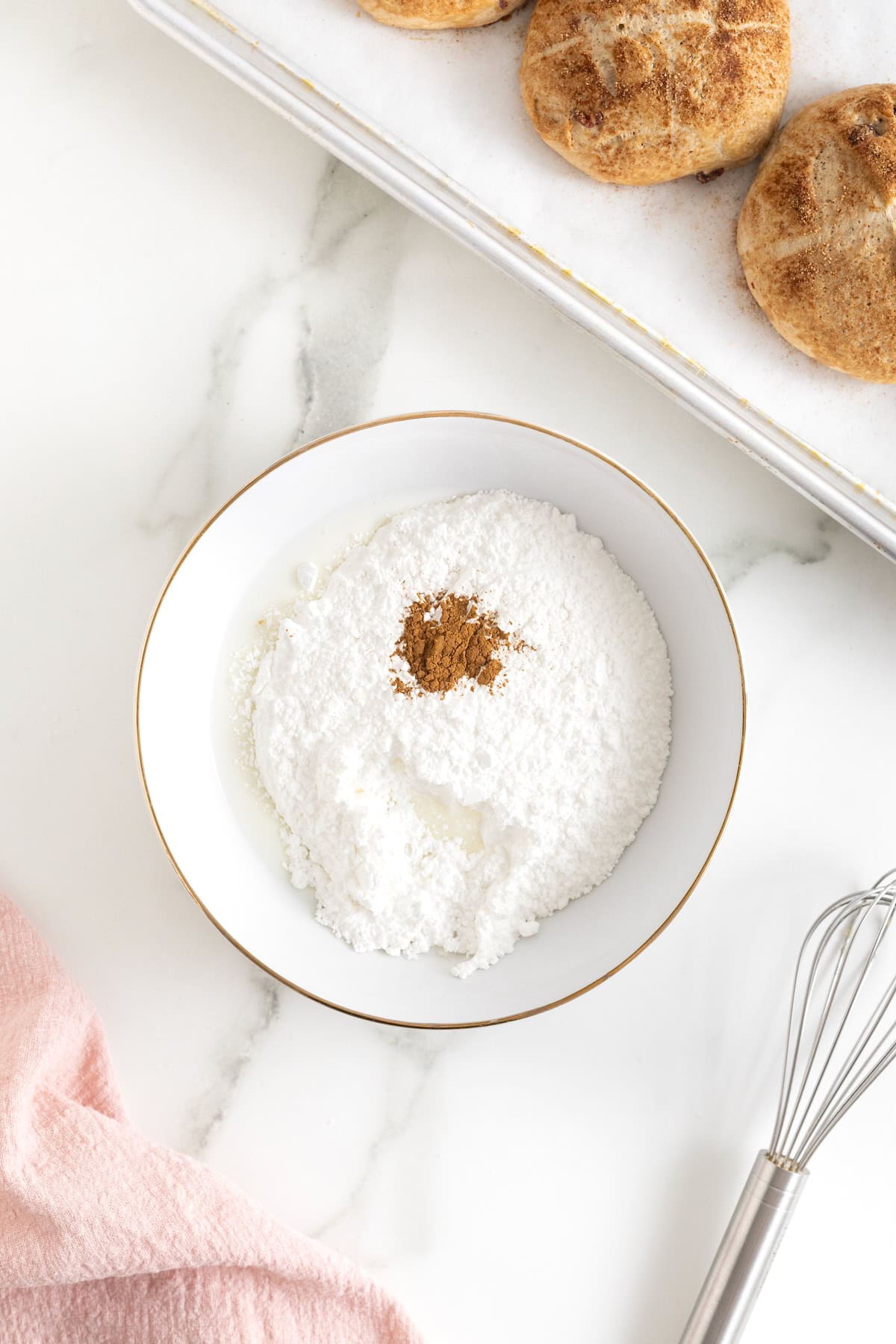Cinnamon and powdered sugar in a white bowl with a gold rim.