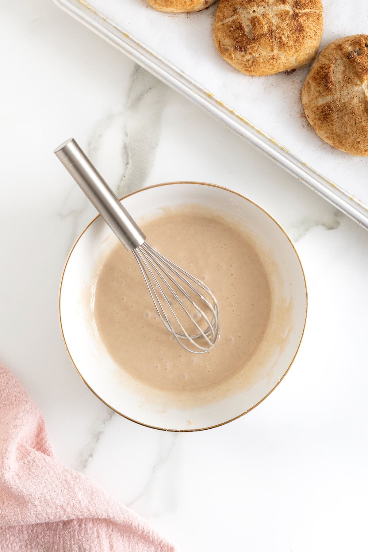 Cinnamon sugar icing in a white bowl with a metal whisk.