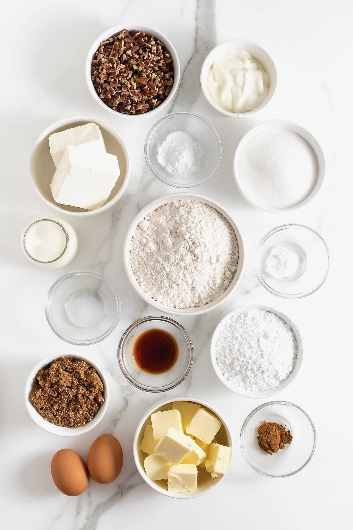 Ingredients to make cream cheese coffee cake in small glass dishes on a white marble counter.