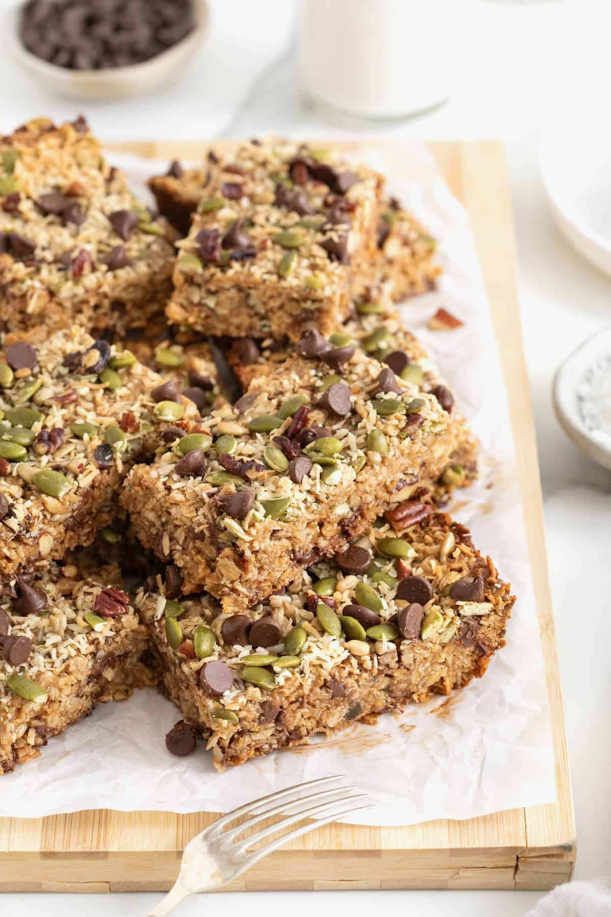A pile of dark chocolate and coconut granola bars with pepitas and chopped pecans.