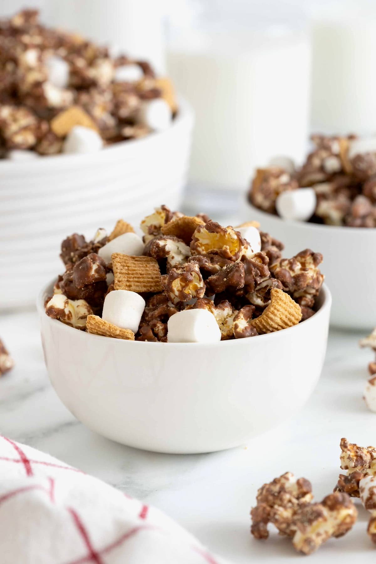 A serving of s'mores popcorn snack mix in a white bowl.