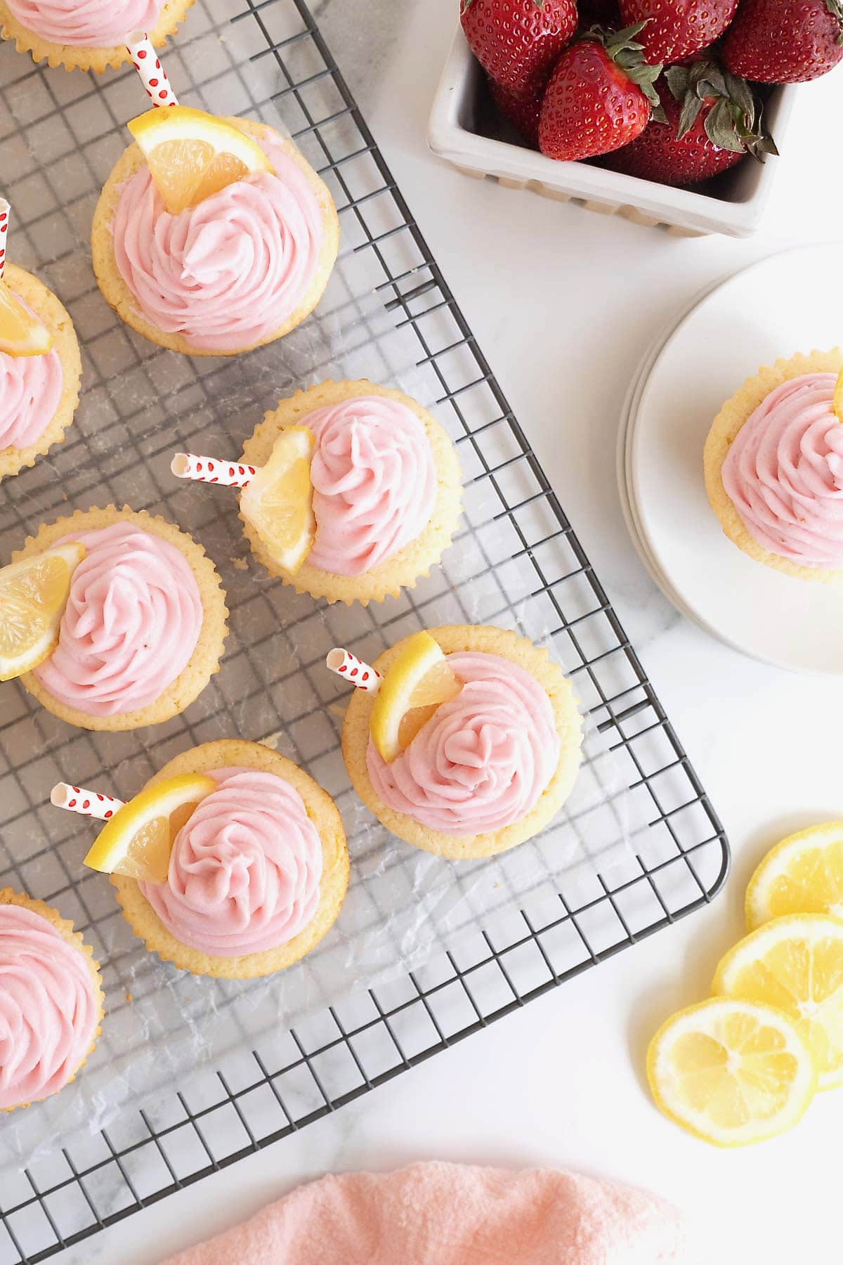Strawberry lemonade cupcakes on a parchment lined wire cooling rack.