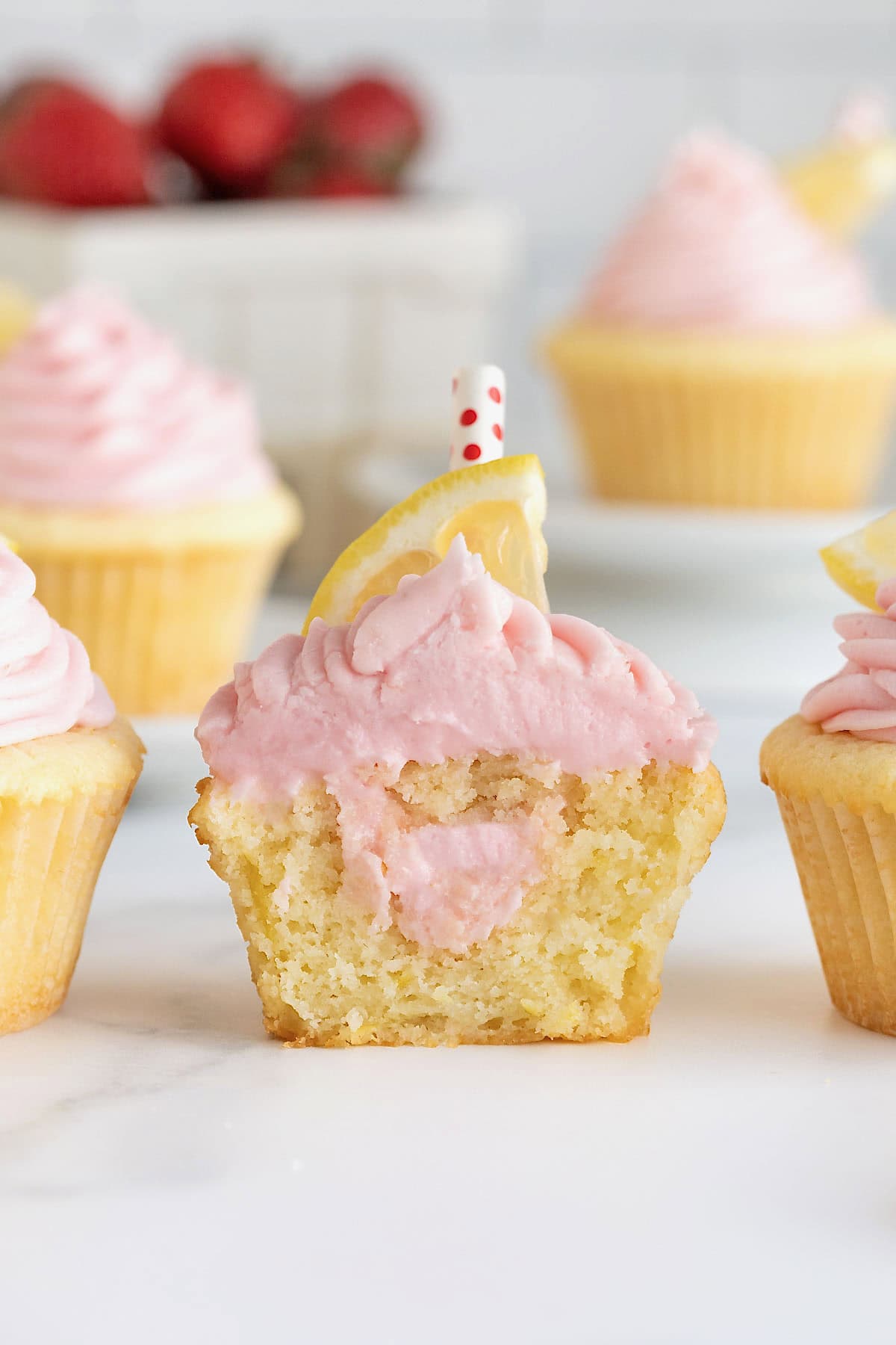 A strawberry lemonade cupcake cut in half to show strawberry frosting filling.