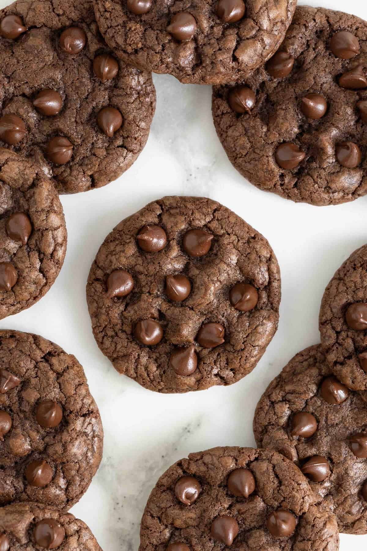 Double chocolate cookies arranged on a white marble counter.