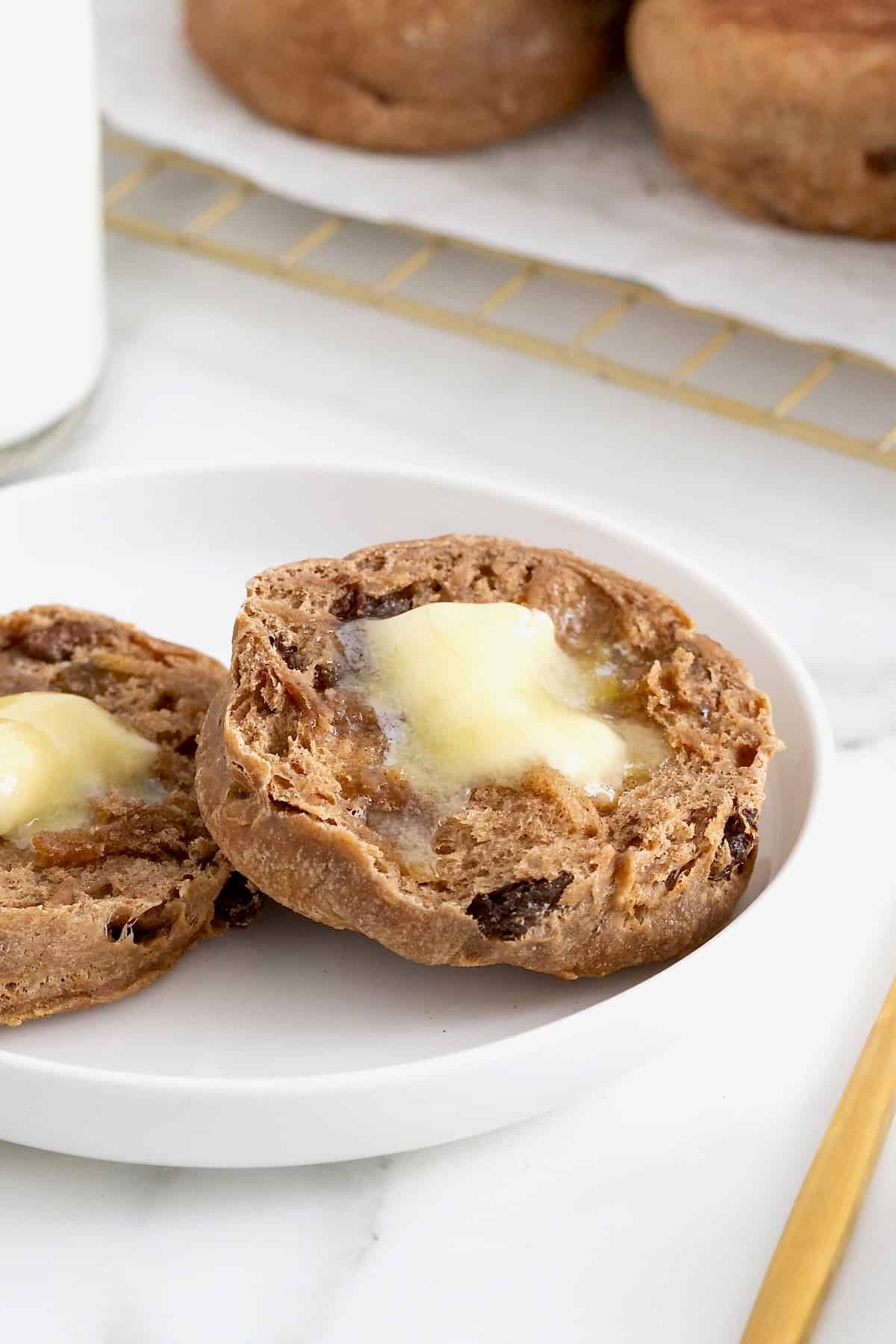 A cinnamon raisin English muffin split in half with butter on each half.