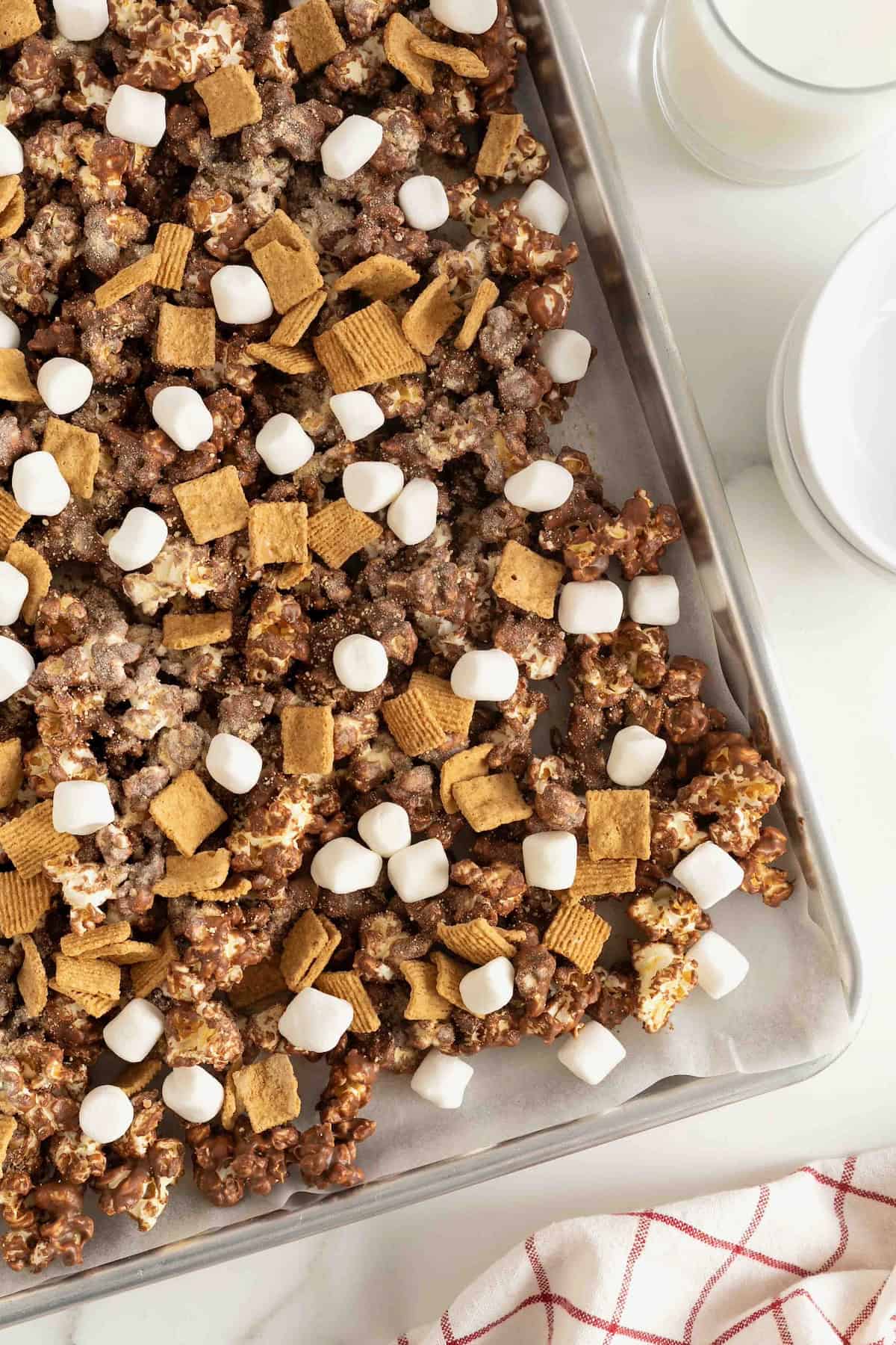 An aluminum sheet pan filled with s'mores popcorn snack mix.