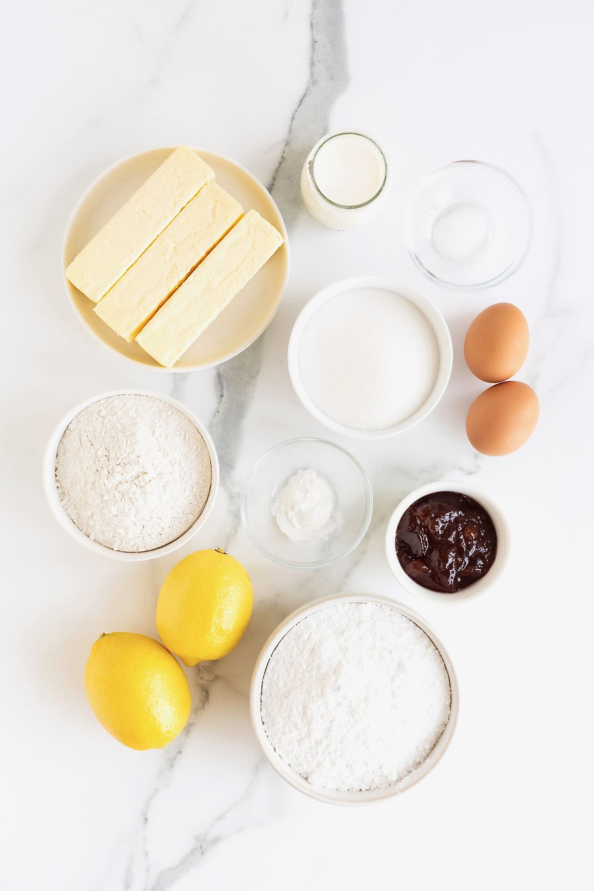 Ingredients to make strawberry lemonade cupcakes in small glass dishes on a white marble counter.