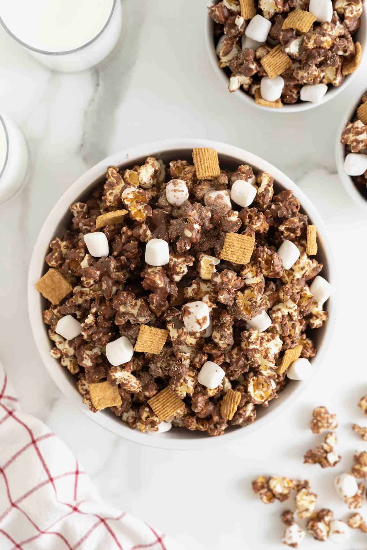 A large white bowl of s'mores popcorn snack mix on a white marble counter.